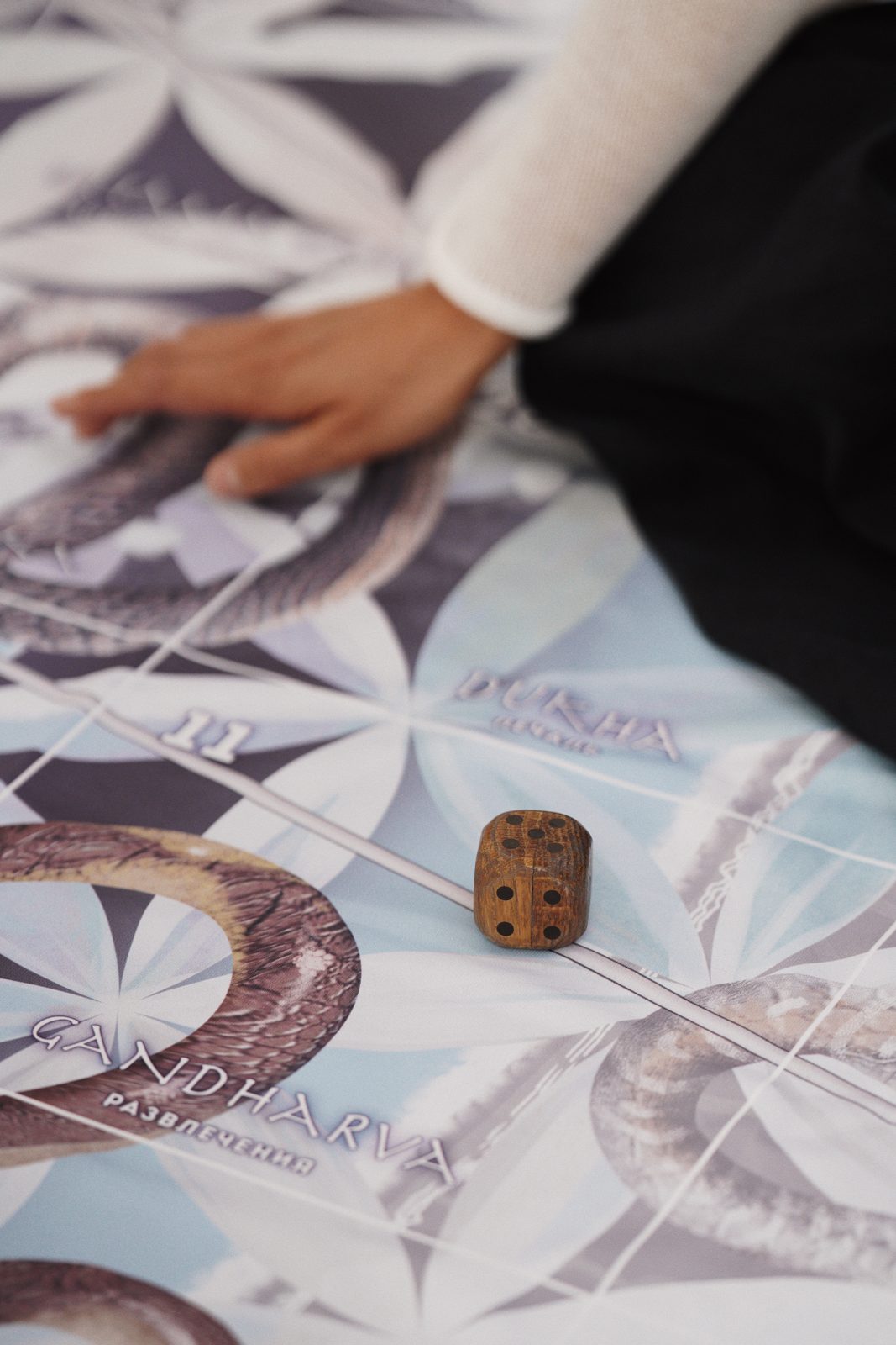 A hand and a die on the Leela board